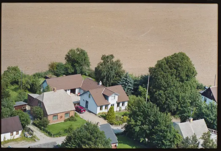 Skråfoto fra luften af pløjede marker på søbunden med huse langs kanten